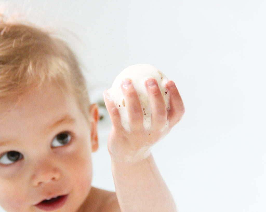 Little kid holding up a Froth Bomb in the tub